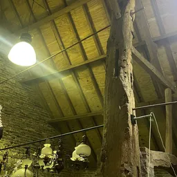 Zolderinterieur met houten balken, bakstenen muur en een felwitte lamp