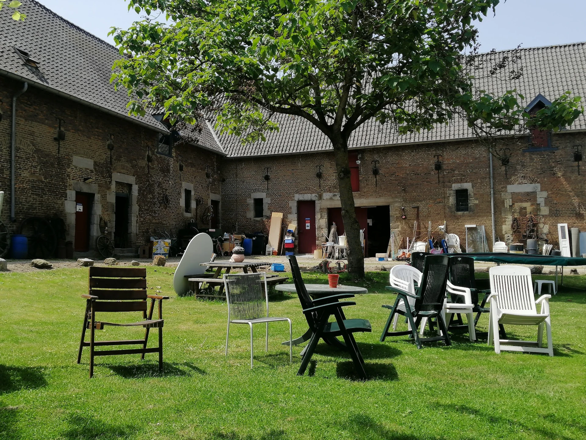 Binnentuin met gras en diverse tuinstoelen rond een tafel, omgeven door bakstenen gebouwen