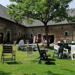 Binnentuin met gras en diverse tuinstoelen rond een tafel, omgeven door bakstenen gebouwen