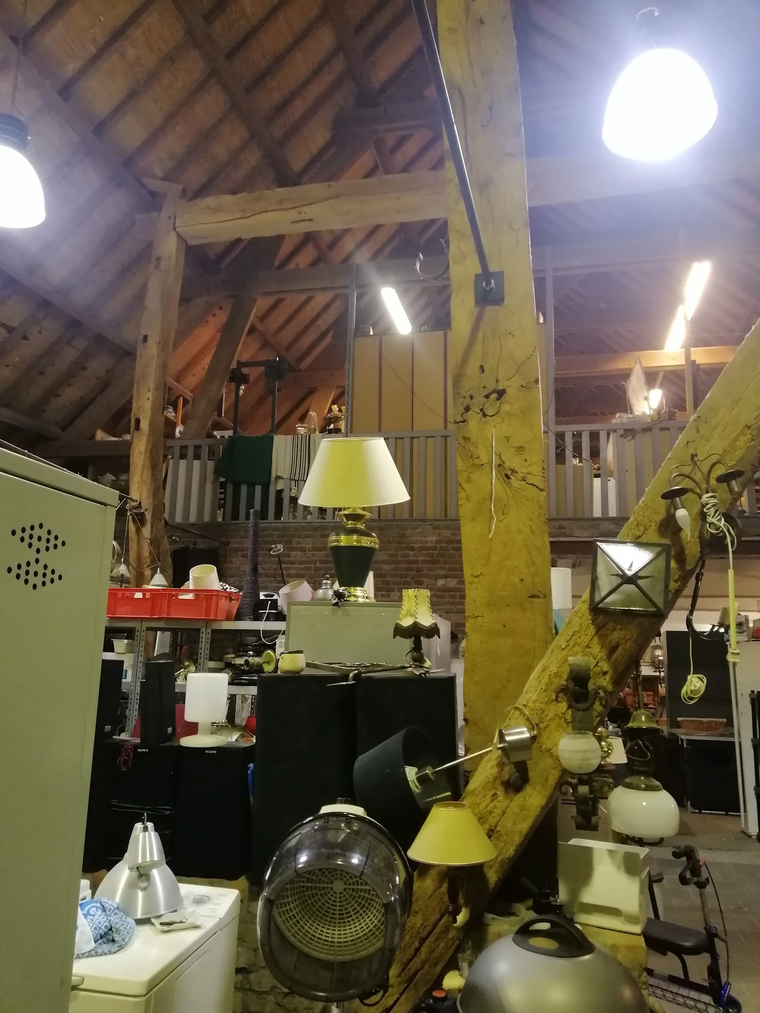 Interieur van kringloopwinkel met diverse meubels, lampen en decoratie-artikelen tussen houten balken