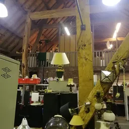 Interieur van kringloopwinkel met diverse meubels, lampen en decoratie-artikelen tussen houten balken