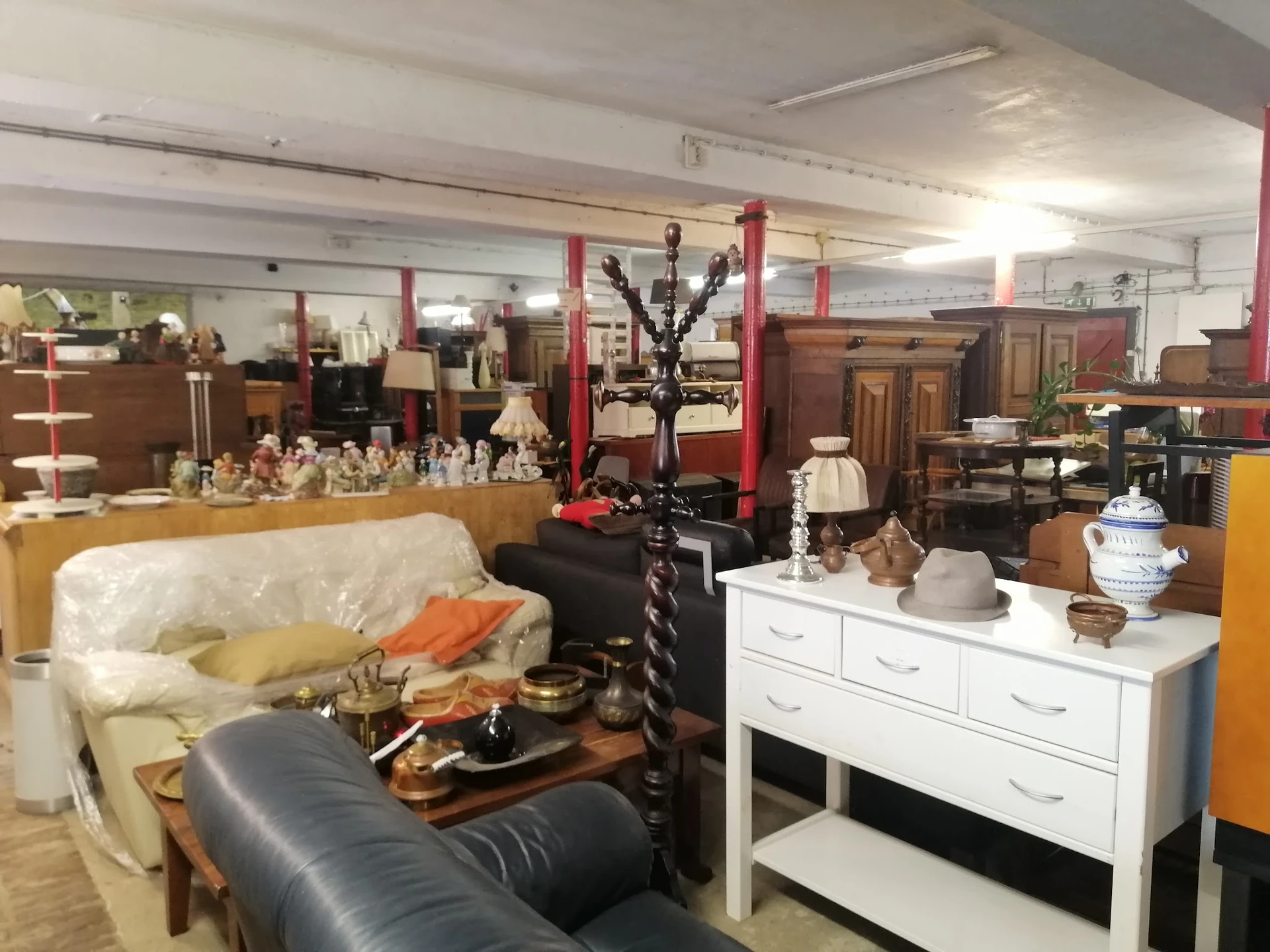 Winkelvloer met meubels en huishoudelijke artikelen, waaronder een bank, witte ladekast en decoratieve objecten