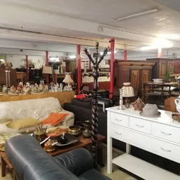 Winkelvloer met meubels en huishoudelijke artikelen, waaronder een bank, witte ladekast en decoratieve objecten