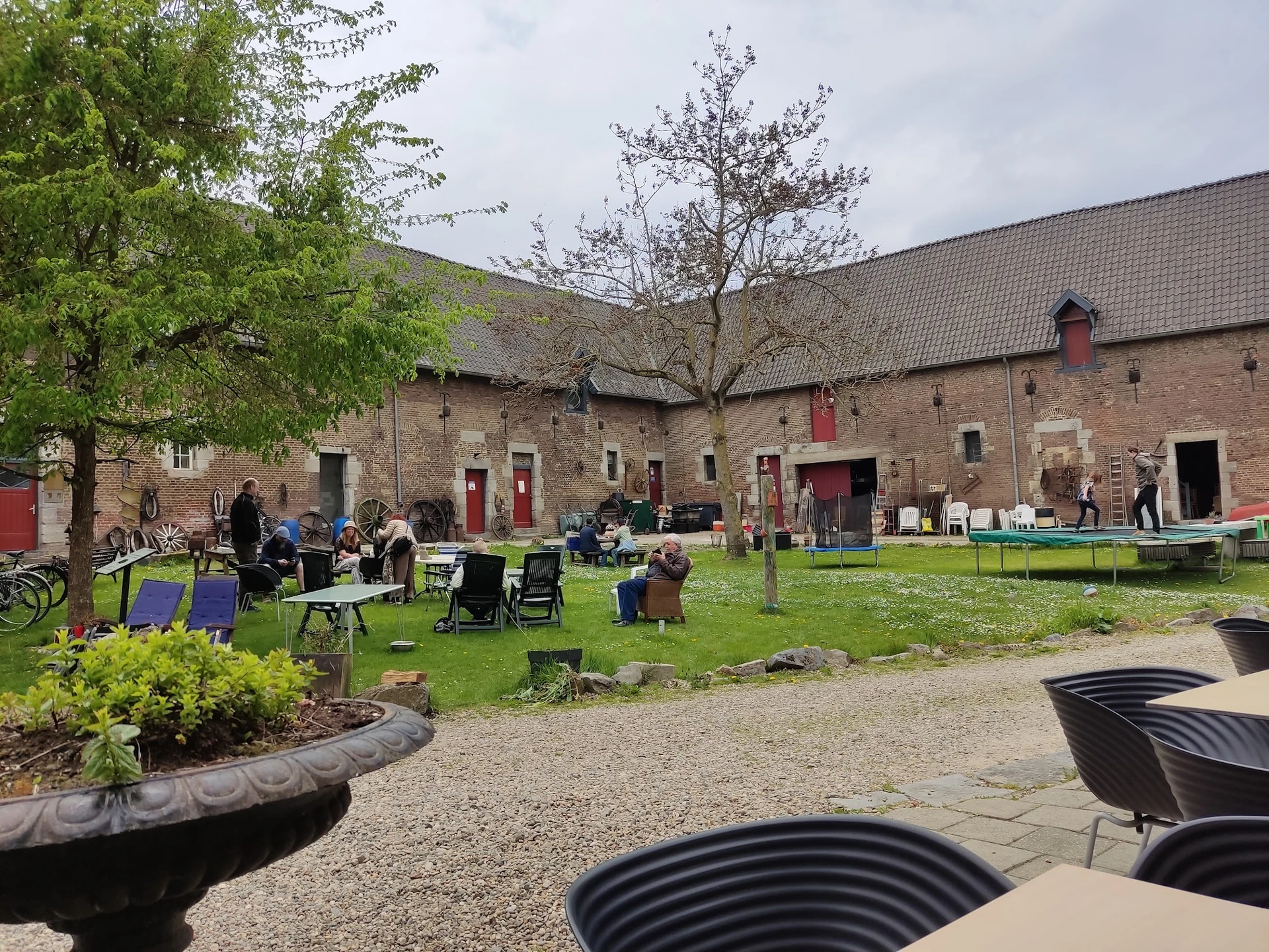Binnentuin met gras, zitplaatsen en bezoekers bij een bakstenen gebouw