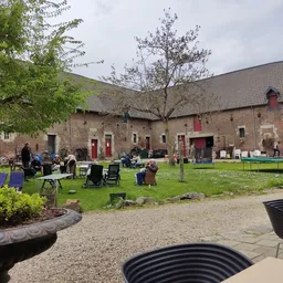 Binnentuin met gras, zitplaatsen en bezoekers bij een bakstenen gebouw