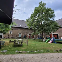 Binnentuin met gras, banken, speeltoestellen en historische bakstenen gebouwen rondom