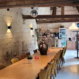 Eettafel met stoelen en gezellige horeca-inrichting met bloemenvaas en kaarsjes