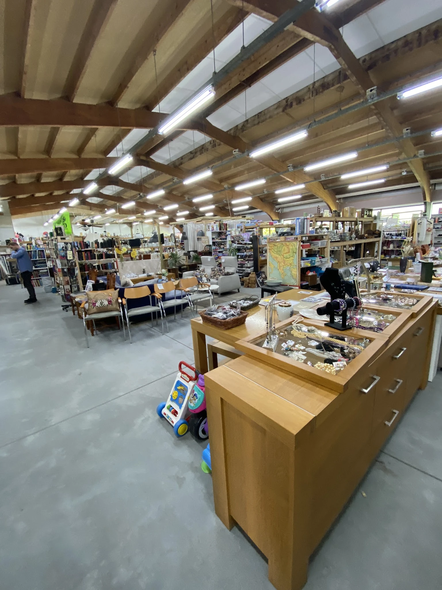 Overzicht van de winkelvloer met stellingen, toonbanken en uiteenlopende tweedehands spullen in een groot magazijn met houten