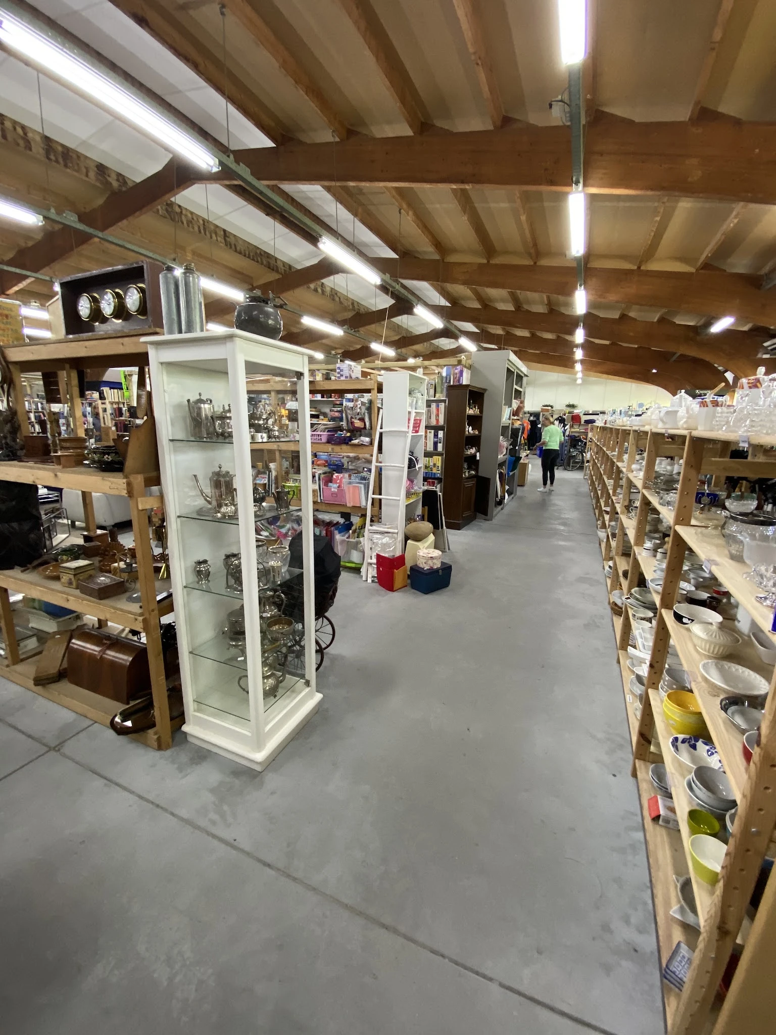 Winkelvloer van kringloopwinkel met stellingen, vitrines en winkelrekken vol spullen