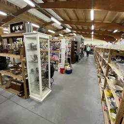 Winkelvloer van kringloopwinkel met stellingen, vitrines en winkelrekken vol spullen