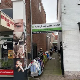 Winkelgevel van Kringloop Zandvoort met etalage en groene winkelscherm aan een straatje