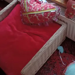 Houten bedframe met rode matras en beddengoedset in kringloopwinkel