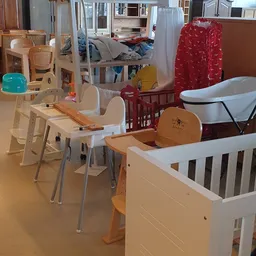 Babymeubilair en babyuitzet in de winkel: hoogstoel, babybadkuip, wieg en houten speelgoedstukken