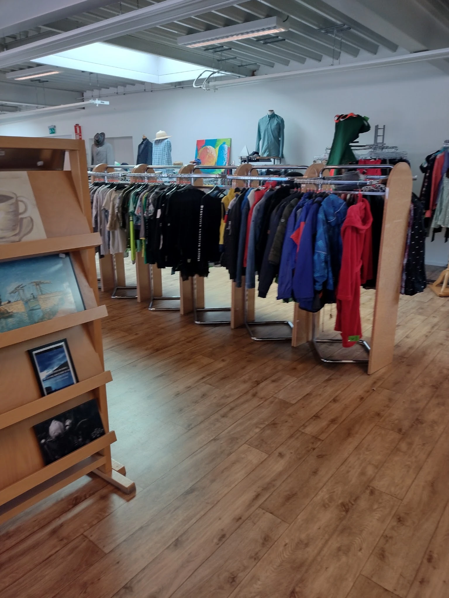 Rekken met tweedehands kleding in verschillende kleuren in een kringloopwinkel