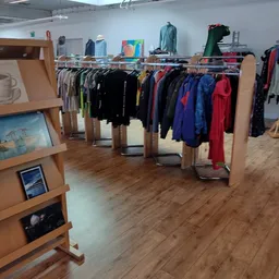 Rekken met tweedehands kleding in verschillende kleuren in een kringloopwinkel