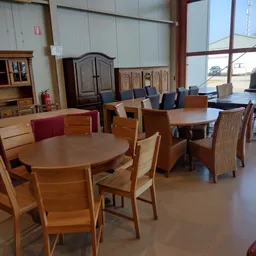 Winkelvloer met houten eettafels en stoelen, kasten en meubels op de achtergrond