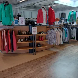 Tweedehands kleding en schoenen op rekken en stellingen in de kringloopwinkel