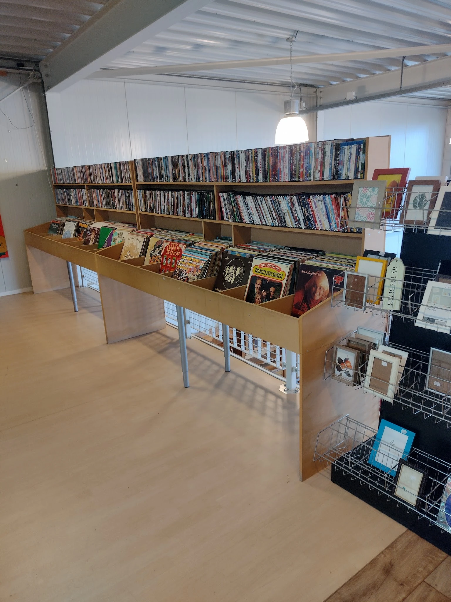 Houten display met dvd's, cd's en boeken uitgestald in de kringloopwinkel
