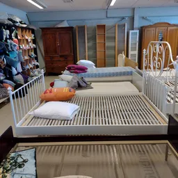 Uitgestalde bedden en matrassen in verschillende maten en kleuren met kussensets in een kringloopwinkel