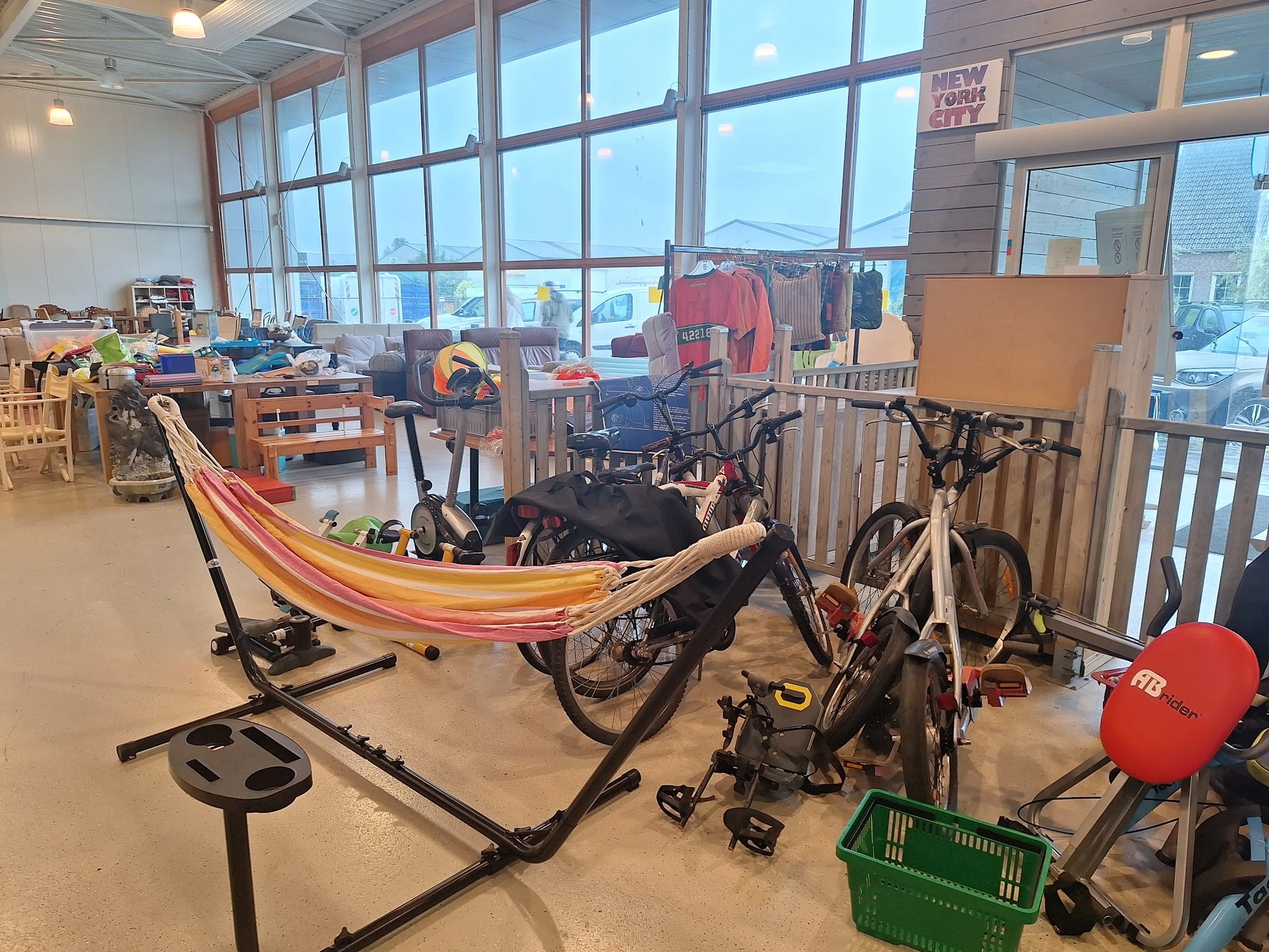 Winkelvloer met speelgoed, fietsen, hangmat en recreatief materiaal langs ramen met uitzicht