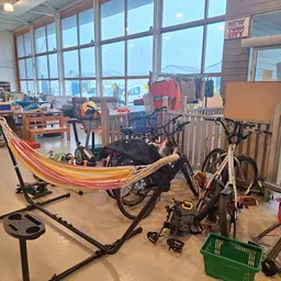 Winkelvloer met speelgoed, fietsen, hangmat en recreatief materiaal langs ramen met uitzicht