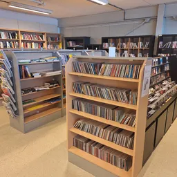 Winkelvloer met houten stellingen vol cd's en dvd's, boeken in achtergrond