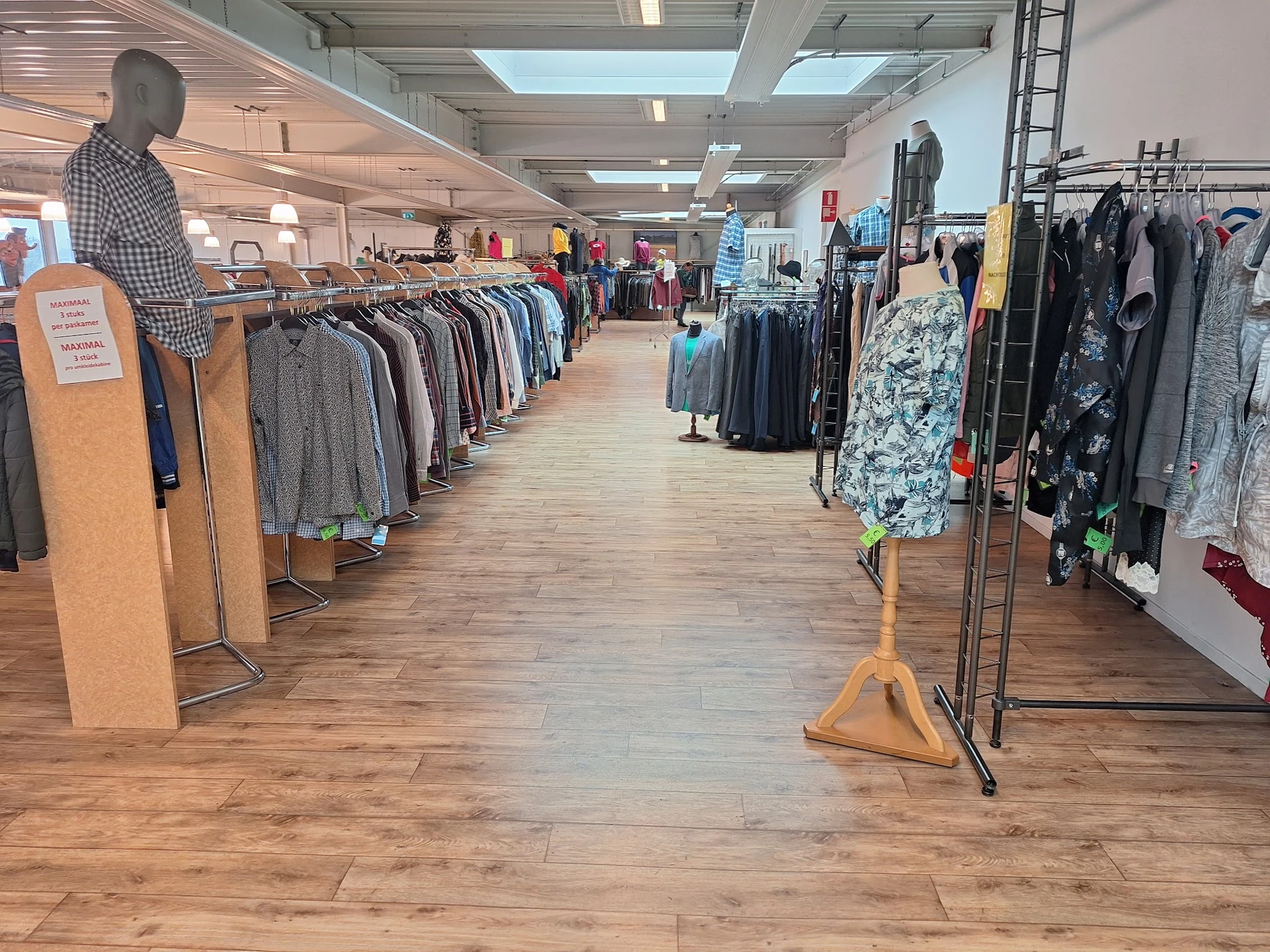 Winkelvloer met kledingrekken vol tweedehands kleding aan beide zijden