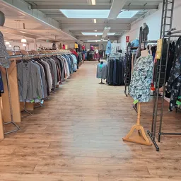 Winkelvloer met kledingrekken vol tweedehands kleding aan beide zijden