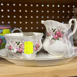 Serviesset met roze bloemmotief: kopje met schotel, kan en schaal op witte achtergrond