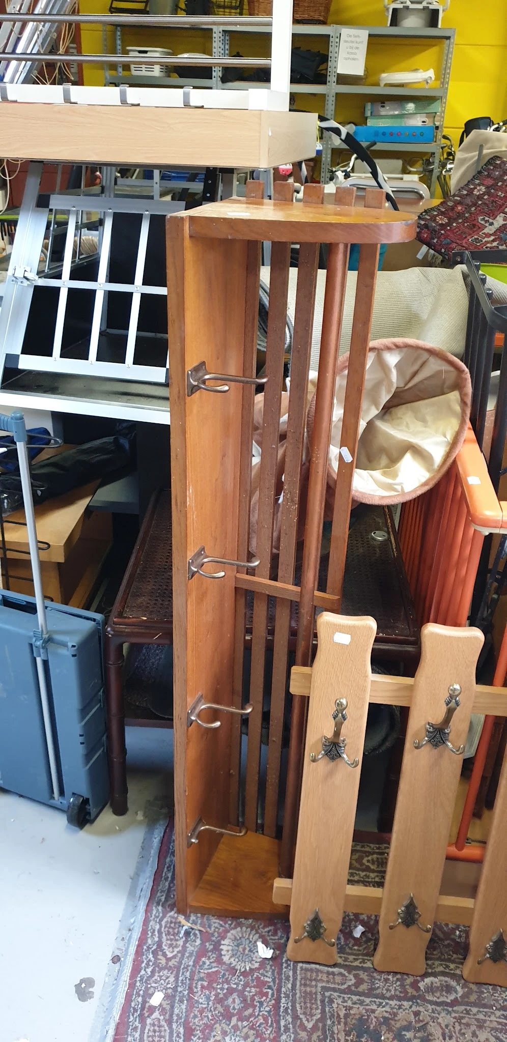 Diverse tweedehands meubels en huishoudartikelen uitgestald in een kringloopwinkel, waaronder stoelen, een kapstok en een ora