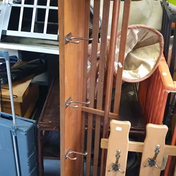 Diverse tweedehands meubels en huishoudartikelen uitgestald in een kringloopwinkel, waaronder stoelen, een kapstok en een ora