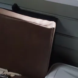 Close-up van een bruin leren meubelstuk met witte rand, mogelijk een bank of stoel