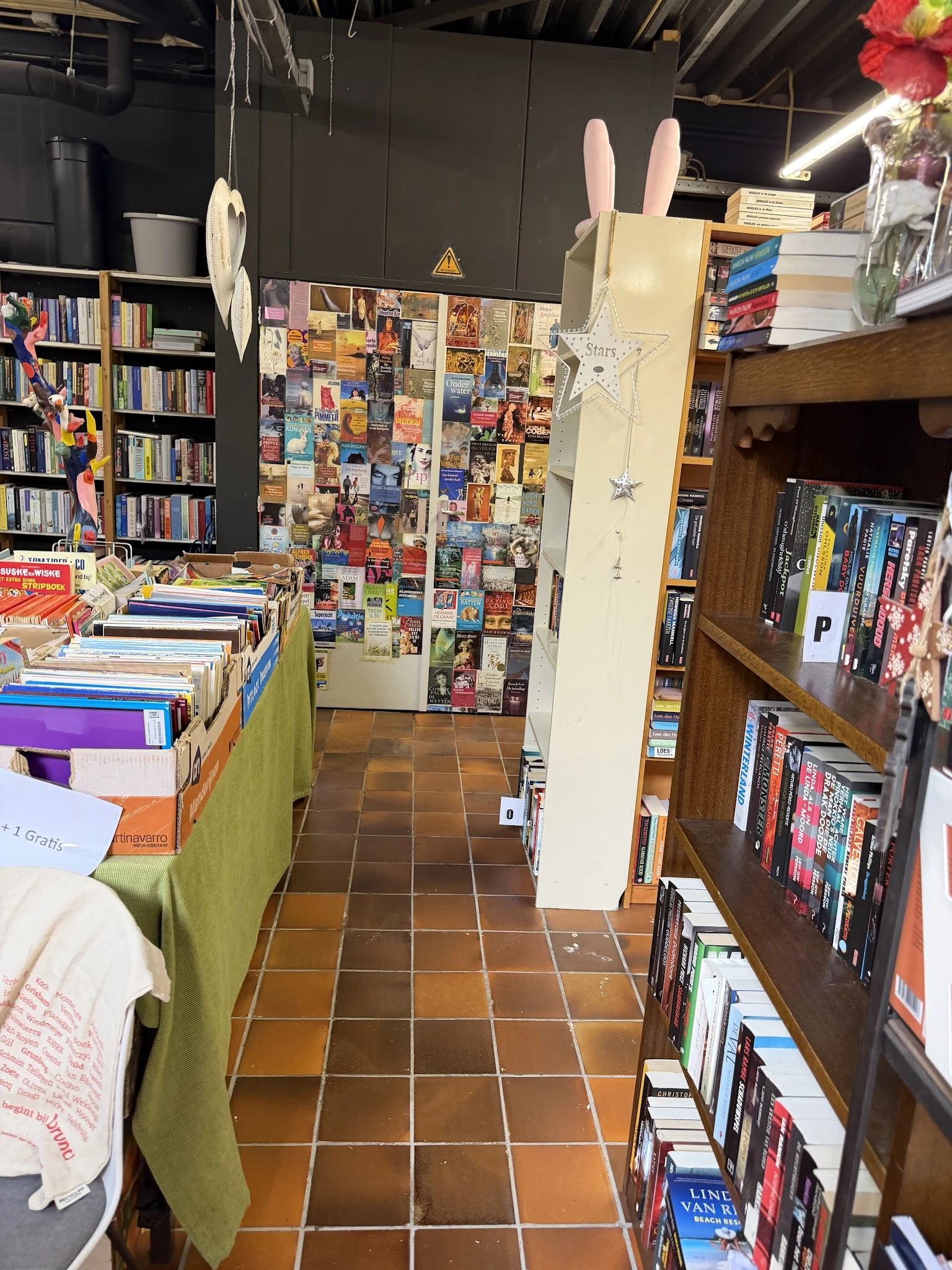 Winkelinterieur met boekenrekken, uitgestalde boeken op tafel en posters aan de muur