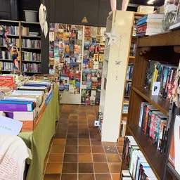 Winkelinterieur met boekenrekken, uitgestalde boeken op tafel en posters aan de muur