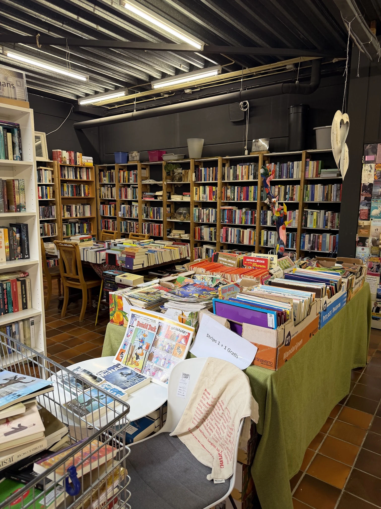 Boekenmarkt in kringloopwinkel met tafels vol tweedehands boeken, achter kasten met nog meer boeken