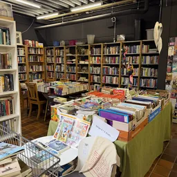 Boekenmarkt in kringloopwinkel met tafels vol tweedehands boeken, achter kasten met nog meer boeken