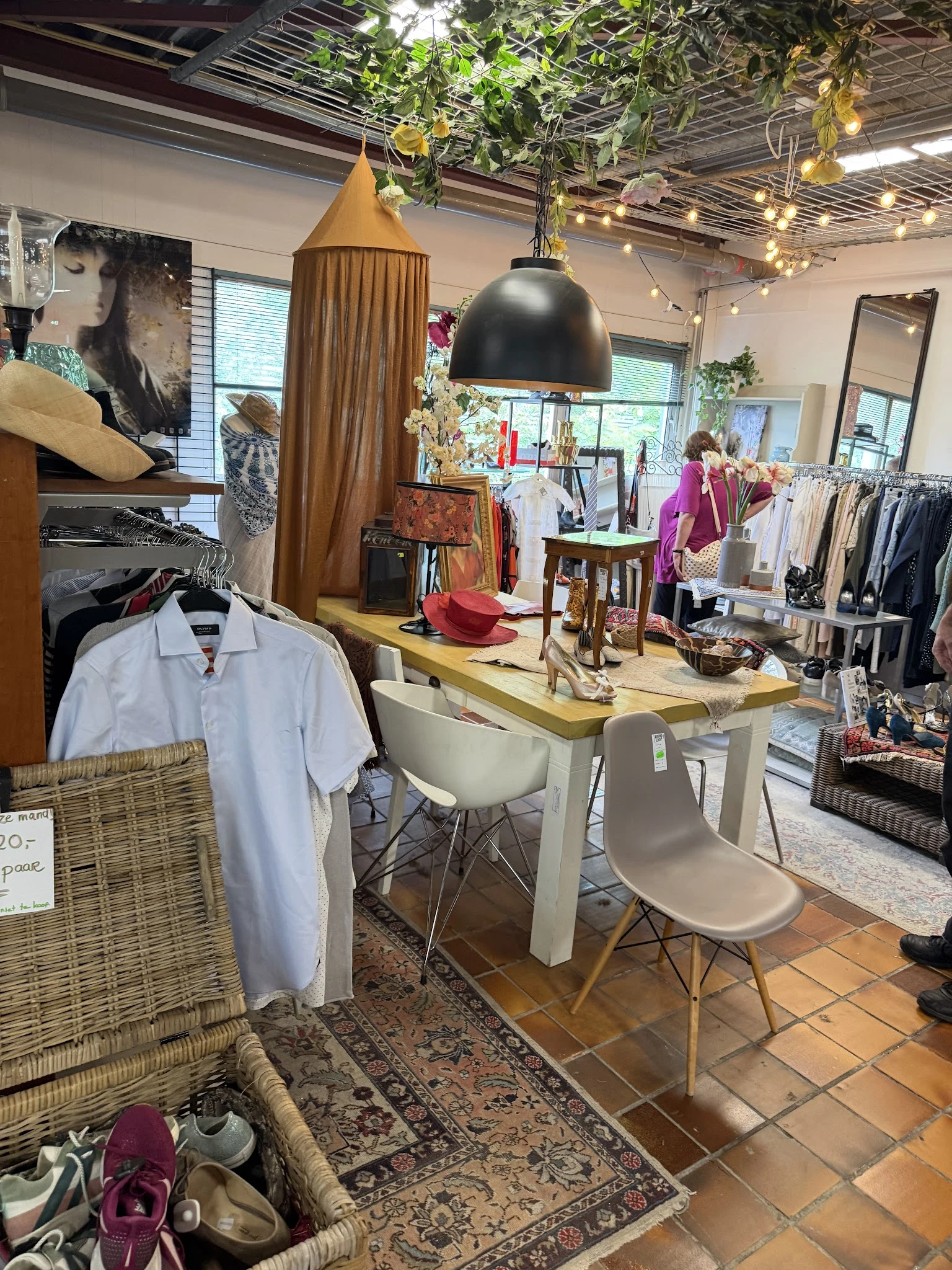 Winkelinterieur met kledingrekken, werktafel met stoel, decoratie en spiegels