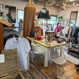 Winkelinterieur met kledingrekken, werktafel met stoel, decoratie en spiegels