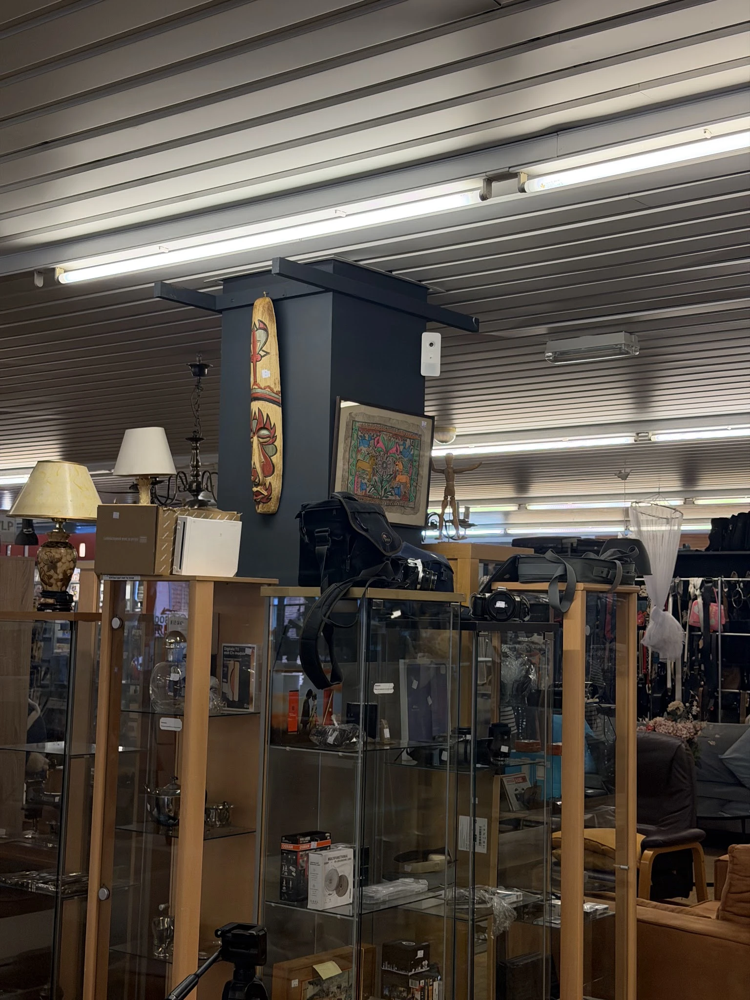 Winkelbinnenruimte met vitrinekasten, lampen en decoratieve items op een centrale zwarte zuil