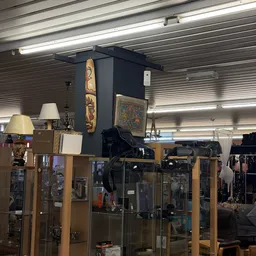 Winkelbinnenruimte met vitrinekasten, lampen en decoratieve items op een centrale zwarte zuil