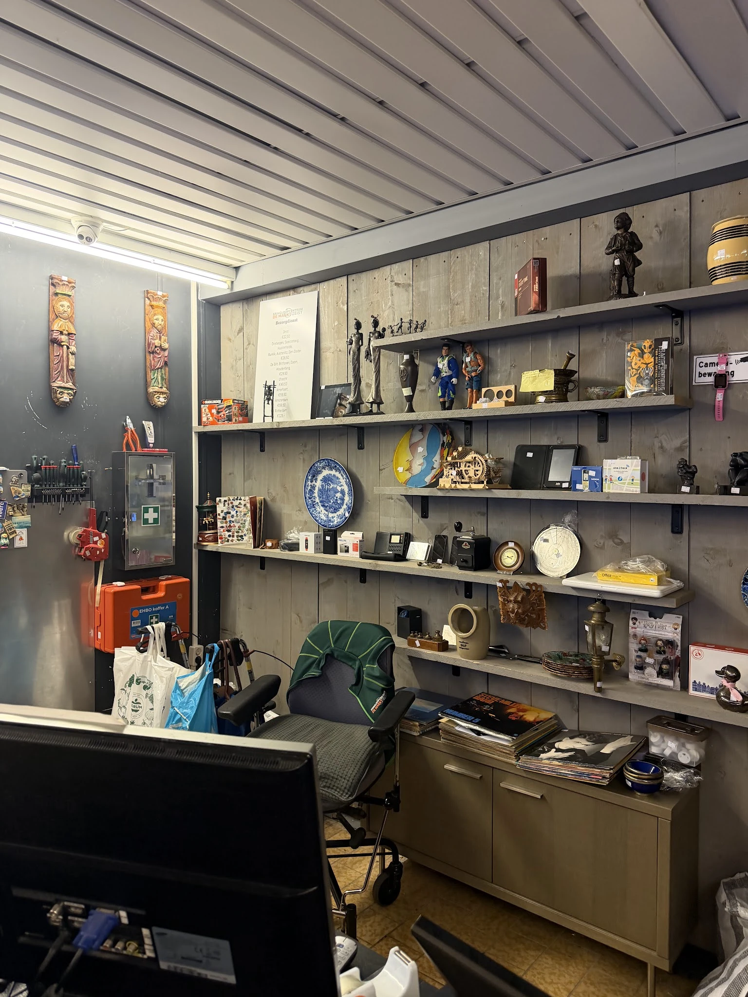 Wandrek met diverse decoratieve items zoals beelden, borden, vazen en antieke voorwerpen uitgestald