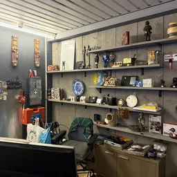 Wandrek met diverse decoratieve items zoals beelden, borden, vazen en antieke voorwerpen uitgestald