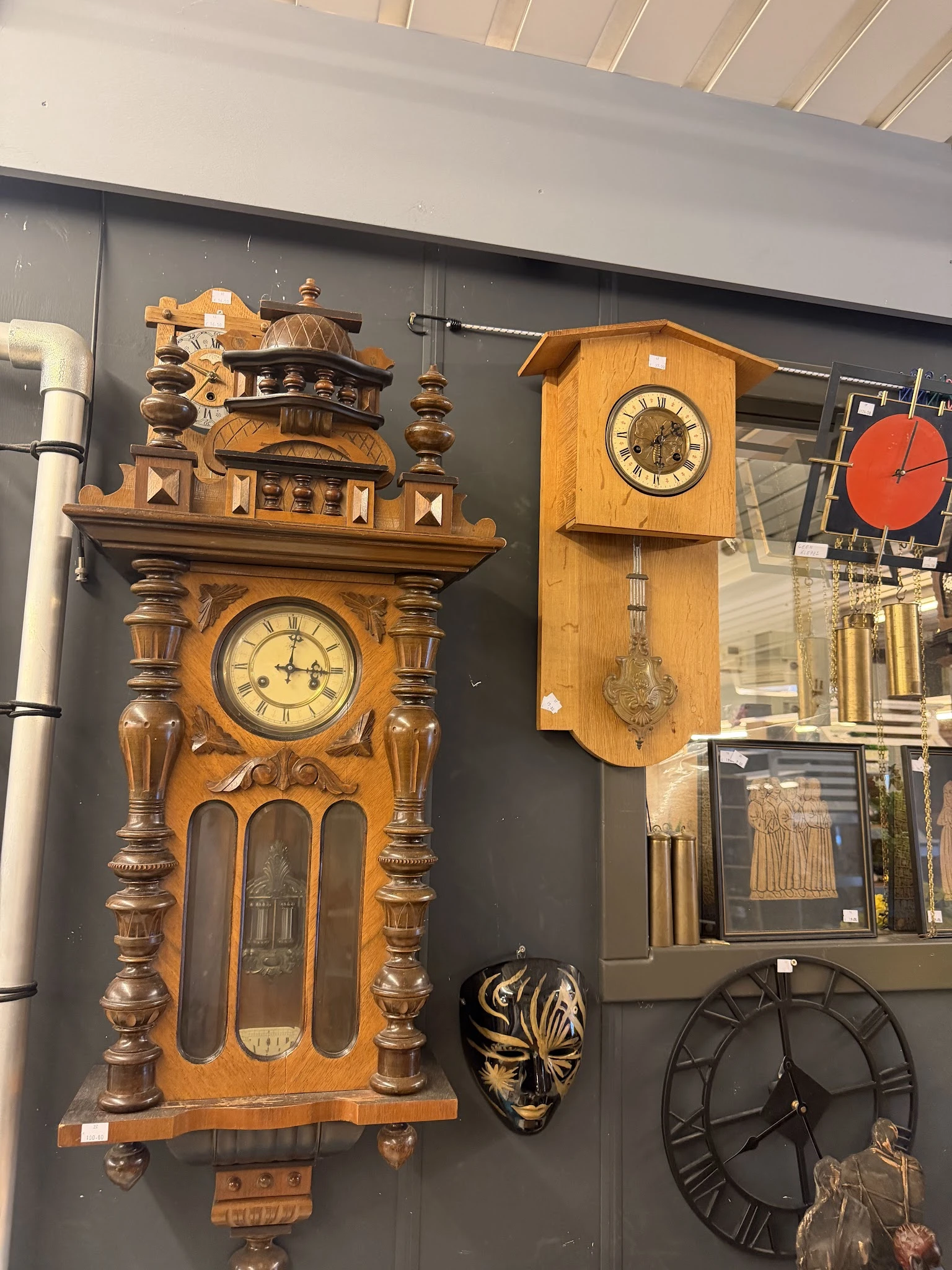 Uitgestalde houten wandklokken en klokken met slingers in de kringloopwinkel