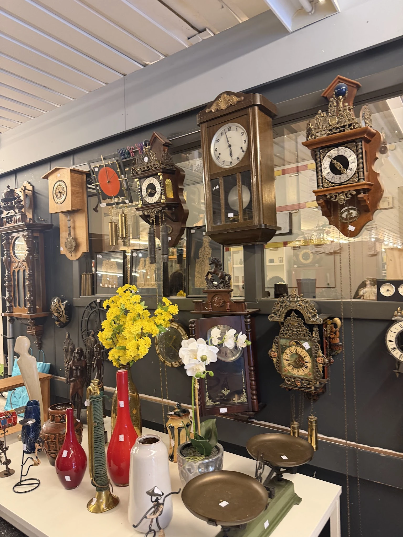 Vitrinekast met verzameling antieke en vintage wandklokken in verschillende stijlen en maten