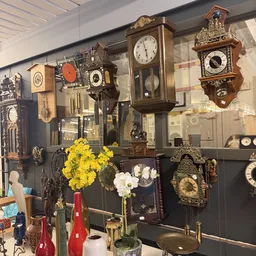 Vitrinekast met verzameling antieke en vintage wandklokken in verschillende stijlen en maten