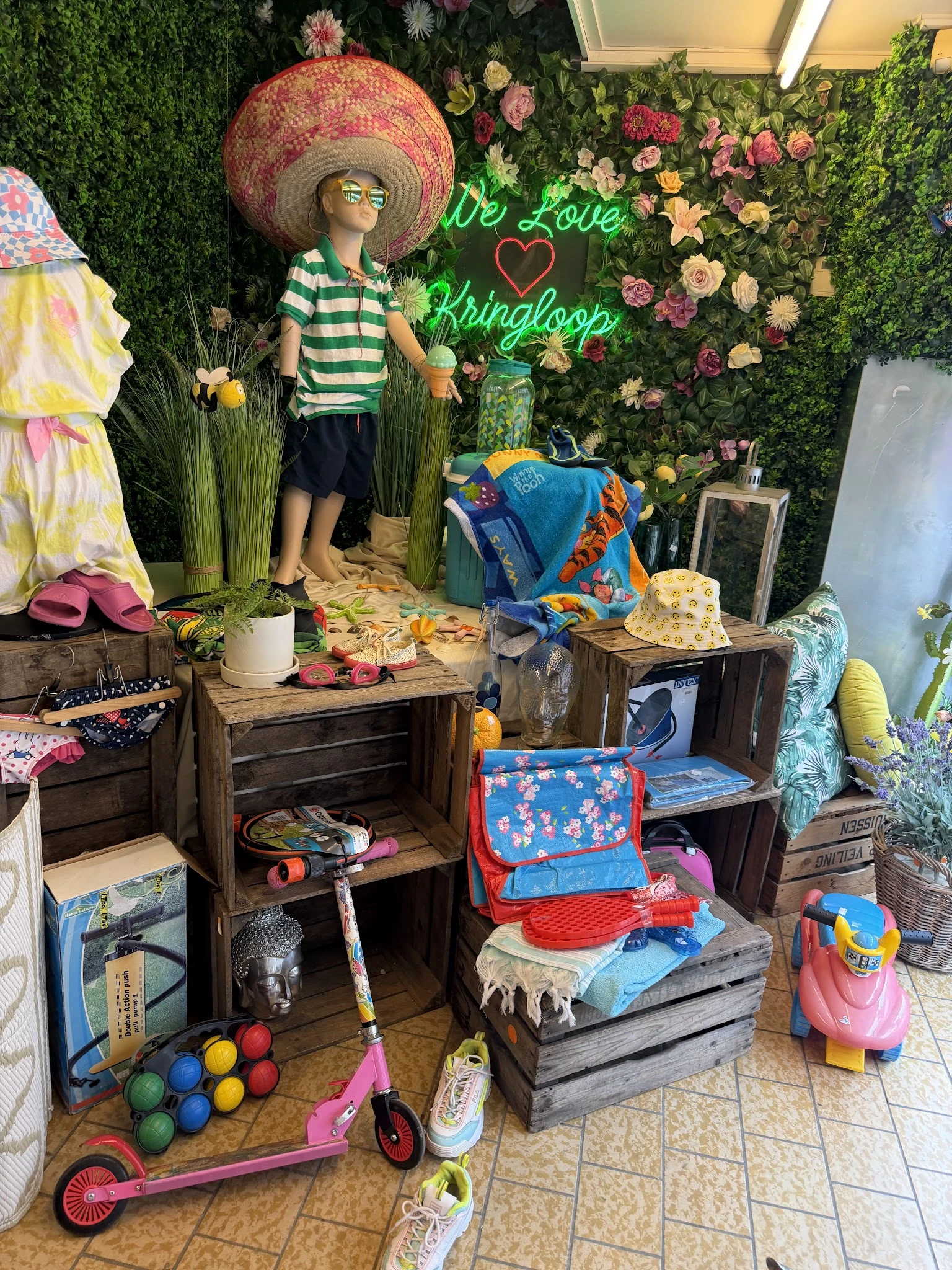 Uitstalkasten en tafels met diverse kinderartikelen, speelgoed en kleding in een kringloopwinkel