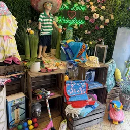 Uitstalkasten en tafels met diverse kinderartikelen, speelgoed en kleding in een kringloopwinkel