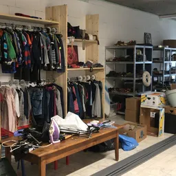 Winkelvloer met houten kledingrekken, uitgestalde tweedehands kleding, kastjes en diverse spullen