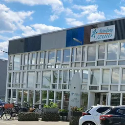 Grijze gevel met grote ramen en blauwe accenten, winkelnaam Kringloop Zuid zichtbaar op bord