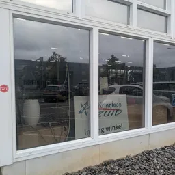 Winkelruit met witte raamkozijnen en gedeeltelijk zichtbare winkellogo van kringloopwinkel